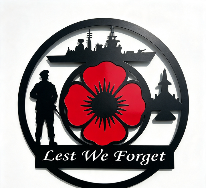 A circular black metal wall plaque featuring a red poppy in the center, silhouettes of a soldier, a ship, a fighter jet, and the text 'Lest We Forget' at the bottom, shown against a plain white background.