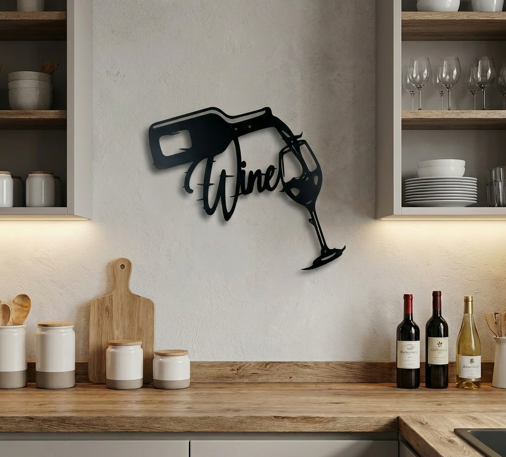 Matte black metal wall art depicting a wine bottle pouring into a glass with the word "Wine" in script, set in a kitchen setting with wine bottles and worktop
